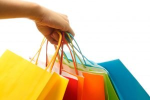 A woman hand carrying a bunch of colorful shopping bags